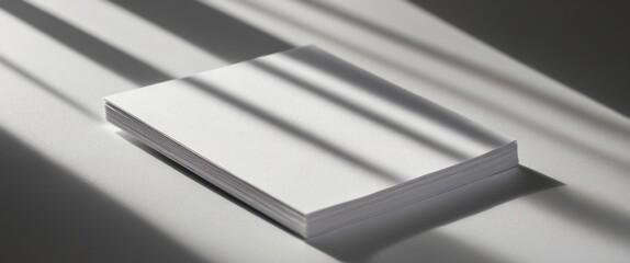 Minimalistic white paper with soft shadows projecting across it, creating a serene and focused atmosphere for design or writing projects.