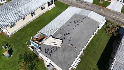 mobile home model with shingles missing and roof damage over a carport