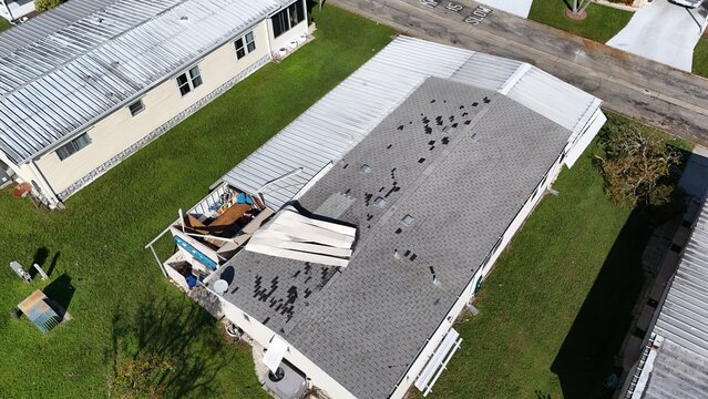 mobile home model with shingles missing and roof damage over a carport
