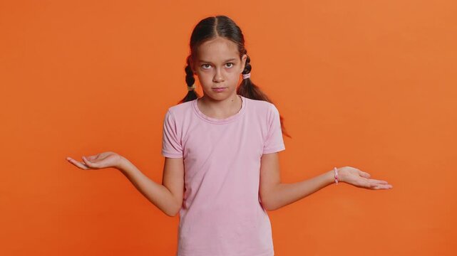 What. Why. Young school girl raising hands in indignant expression asking why what reason of failure demonstrating disbelief irritation by troubles. Preteen child kid 10 years old on orange background