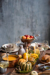 A table with a variety of food and drinks, including a pumpkin, a bowl of soup