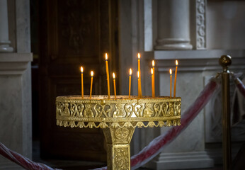 Lighted candles on the golden stand in Russian Orthodox Christian cathedral