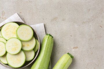 Fresh cut and whole zucchinis on grey textured table, flat lay. Space for text