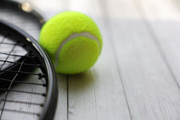 Yellow tennis ball lying on a white tree, next to it are close-up tennis rackets with space for text. High quality photo