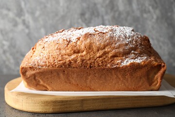 Tasty sponge cake with powdered sugar on grey table, closeup