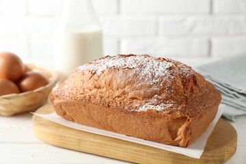 Tasty sponge cake with powdered sugar on white table, closeup