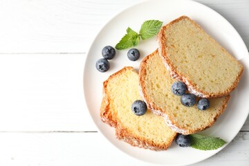 Freshly baked sponge cake, mint and blueberries on white wooden table, top view