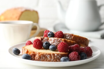 Freshly baked sponge cake, raspberries and blueberries on white wooden table, closeup