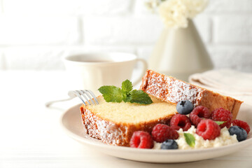 Freshly baked sponge cake, whipped cream, berries and mint on white wooden table, closeup