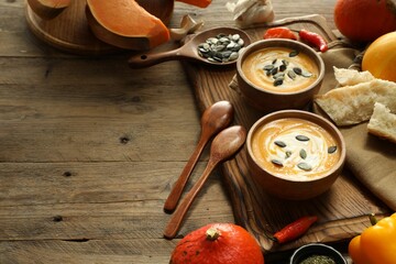Delicious pumpkin soup served on wooden table, space for text