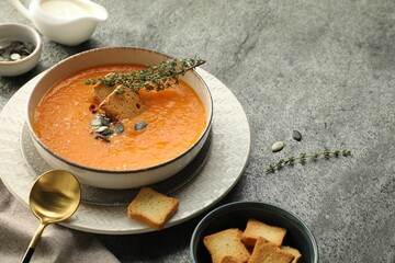 Delicious pumpkin soup with spices and croutons on grey textured table, closeup. Space for text