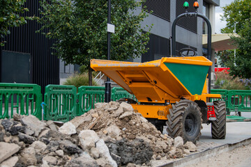 3 ton site swivel dumper with blurred rubble in front surrounded by safety green pedestrian barrier...