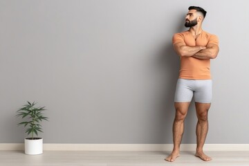 Confident man in casual home setting with potted plant on wooden floor