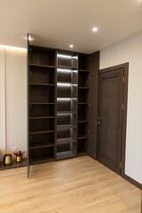 Modern apartment interior with sleek shelving unit and warm wooden flooring creating an inviting space for design enthusiasts