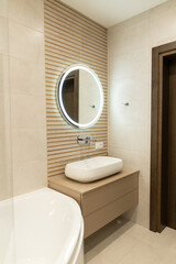 Elegant modern apartment bathroom with innovative design elements featuring a circular mirror and sleek cabinetry