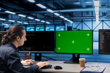 Admin in data center using diagnostic tools and system monitoring software on green screen PC to...