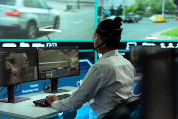 Indian expert looking at surveillance footage in a monitoring room, working on tracking license plates through CCTV security system cameras. Employee gather public information via radar.