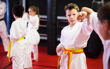 Karate kids in kimono sparring together during their group karate training.