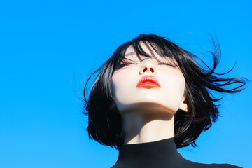 青空の下で風を感じる日本人女性