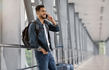 Roaming Abroad. Portrait Of Handsome Arab Man Talking On Cellphone In Airport, Happy Smiling Middle Eastern Guy Enjoying Phone Conversation While Waiting For Flight In Terminal, Copy Space