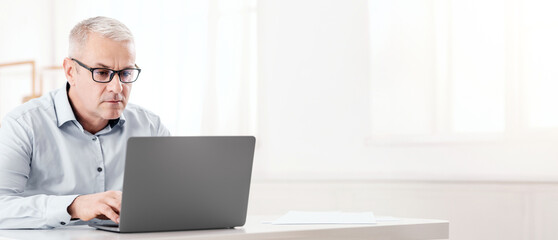 Web Surfing Concept. Focused Senior Man In Specs Using Wifi Working On Laptop, Free Space