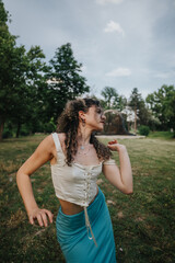 Obraz premium A joyful young girl dances with carefree spirit amidst the serene environment of a lush green park. Her expressive movement captures the essence of freedom and happiness.