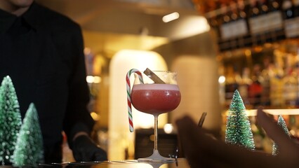 Focused mixed punch cocktail Christmas theme garnishing with burning cinnamon and star anise by bartender, serving decorated green neon snow Christmas tree bar special cool drink luxury. Vinosity.