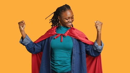 Happy superhero flexing muscles to prove force, listening music, isolated over studio background....