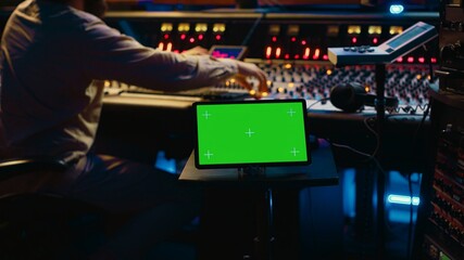 Sound designer processing and recording tracks in control room, using mixing console and sliders to...