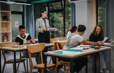Students actively participate in a classroom setting, engaging in discussion and learning activities with peers and a teacher, showcasing an interactive academic environment.