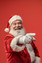 Naklejka premium Santa claus pointing finger on empty space. Christmas advertising. Red background. High quality photo