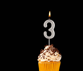 Number 3 shaped candles - Birthday cupcake on black background.