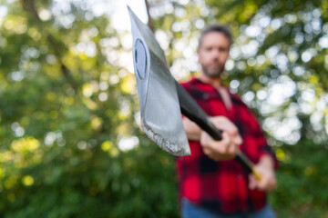 Cutting wood. Sharp blade. Brutality and masculinity. Lumberjack with axe in selective focus....