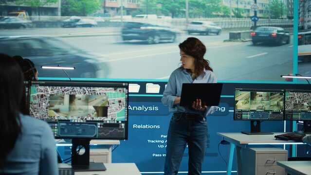 Supervisor gathering intelligence from satellite based surveillance footage, diverse team of operators analyzing traffic through security cameras. Control center license plate reading. Camera B.