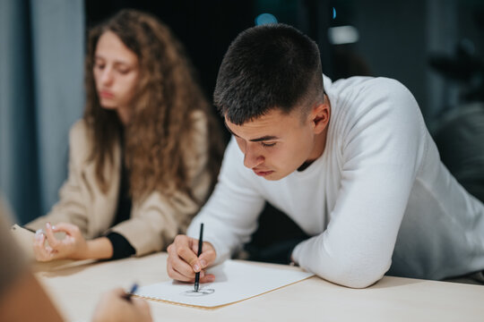 A young man and woman intensely focusing on their assignments in a classroom environment, showcasing dedication and concentration during a study session.