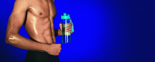 Unrecognizable Black Fitness Guy Holding Bottle Of Water Drink During Workout On Blue Studio Background. Cropped, Panorama
