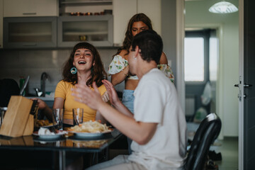 Three friends share a joyful moment in a modern kitchen, laughing and chatting around a table filled with snacks. The atmosphere is relaxed and cheerful, reflecting a warm social gathering.