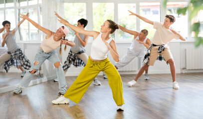 Dynamic juvenile girl engaged in active dance together with other attendees of dancing courses