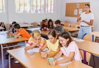 Schoolchildren use mobile phones at the lesson in the classroom
