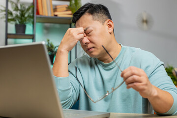 Displeased sad Asian man use laptop notebook typing browsing working, loses becoming surprised...