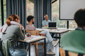 A group of students attentively listening to an elderly professor in a modern classroom setting, fostering an engaging learning environment.