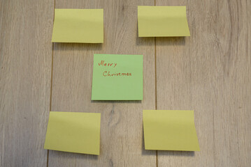 Merry Christmas written on sticky notes on a wooden background