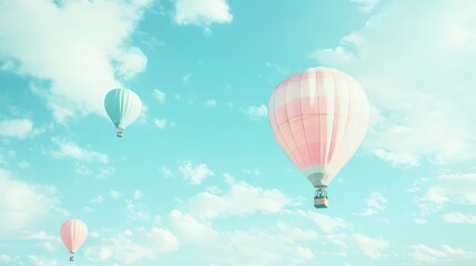 Three pastel hot air balloons float in a clear blue sky.