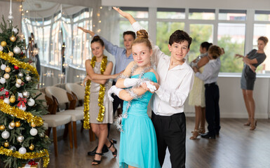Teenagers in holiday clothes dancing swing dance near the Christmas tree