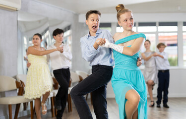 Obraz premium During rehearsal of reporting concert, adolescence boy and girl participants of dance workshop perform lindy hop under guidance of female mentor
