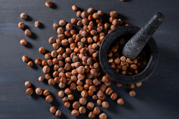 Raw hazelnuts in a stone mortar against a dark background