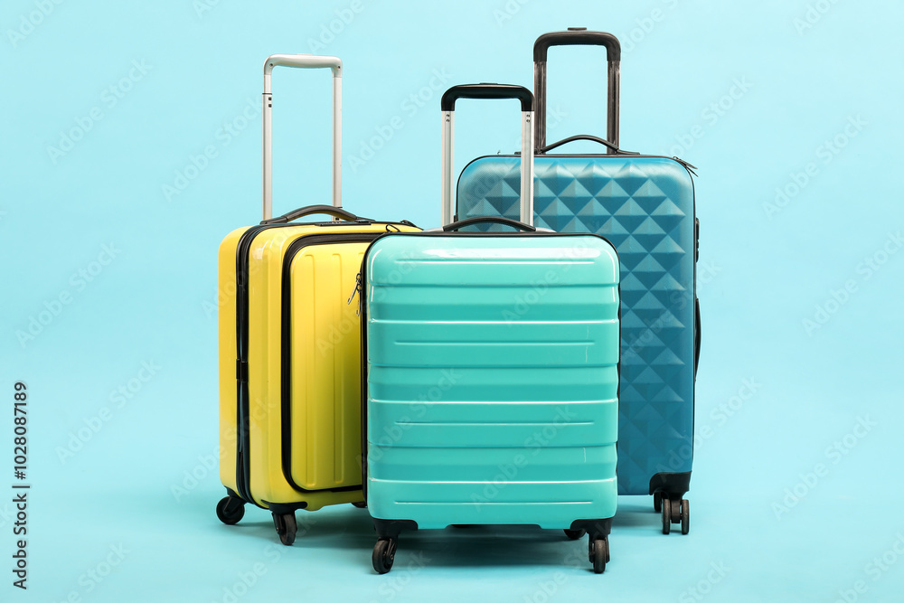 Poster Different bright suitcases on light blue background