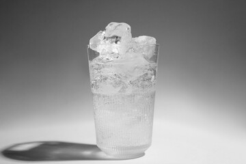 Refreshing water with ice in glass on grey background