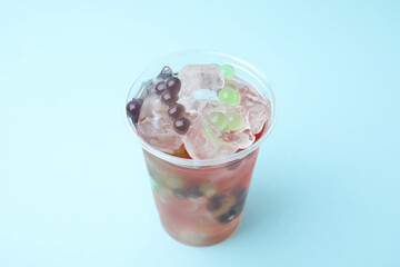 Tasty bubble tea in plastic cup on light blue background