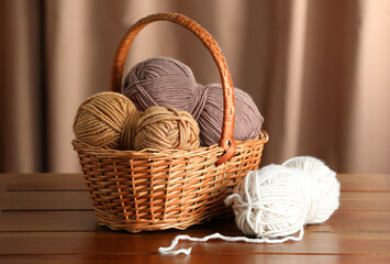 Knitting material. Wicker basket with skeins of soft yarn on wooden table